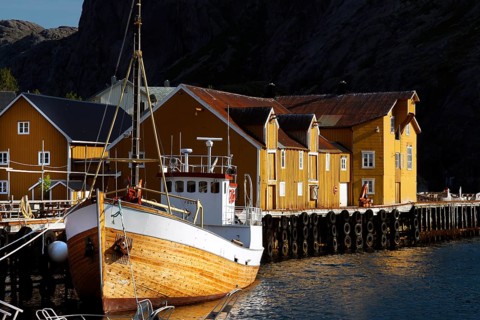 Yellow wooden house and boat in Nusfjord harbour, Flakstadøy, Nusfjord, Flakstadøy, Norway