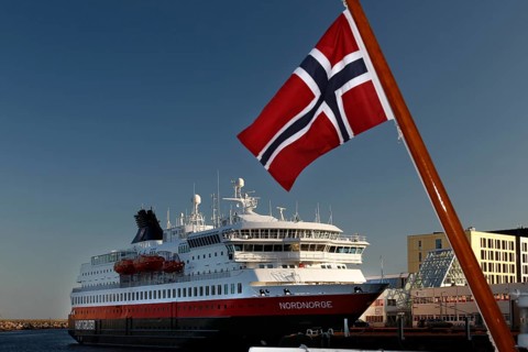 Hurtigruten ship with Norwegian flag in Svolvær harbour, clear visibility and blue sky, Svolvær,