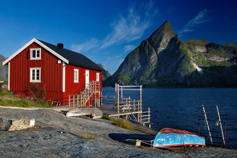 Red rorbu on the water with mountain panorama on Moskenesøy, Sakrisøy, Moskenesøy, Lofoten