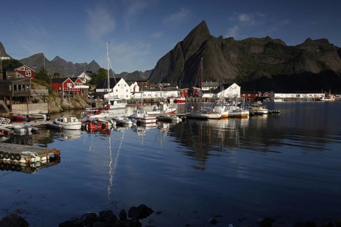 Sakrisøy harbour, where boats lie in calm water against a majestic mountain backdrop, Sakrisøy,