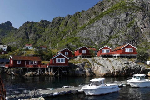 Red rorbuers and boats along Sakrisøy's rocky coast in Lofoten, Sakrisøy, Moskenesøy, Norway