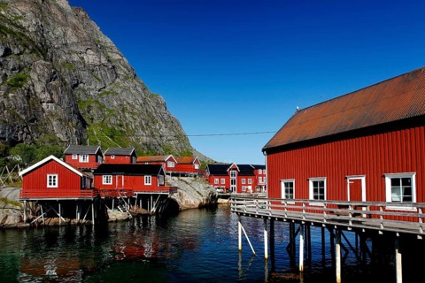 Red fishermen's houses in Sakrisøy against the majestic Lofoten mountains, Sakrisøy, Moskenesøy,