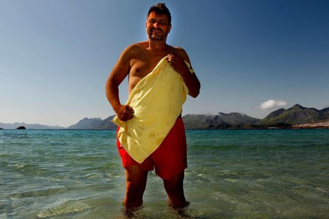 Summer day on Austvågøy beach with a man in the warm, clear water of Lofoten, Lofoten, Nordland,