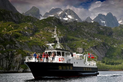 Tourists enjoy a boat trip in Trollfjord with mountain backdrop, Austvågøy, Raftsund, Norway