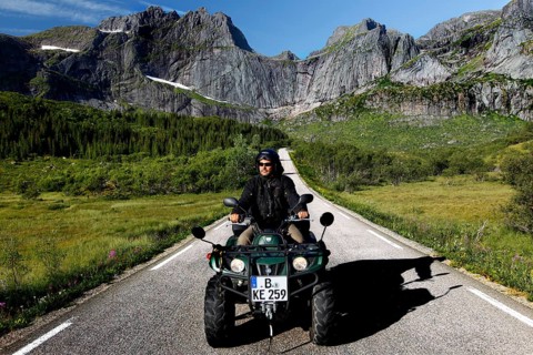 Person riding on ATV on a picturesque road in Flakstadøy, Flakstadøy, Lofoten, Norway