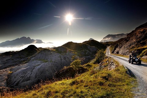 ATV rides through the rolling countryside of Lofoten under dazzling sunlight, Vestvågøy,
