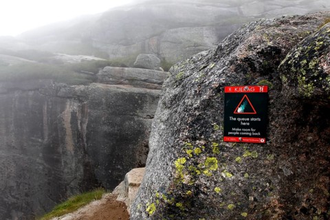 Warning on rock against the backdrop of the misty Kjerag landscape, Lysefjord, Rogaland, Norway