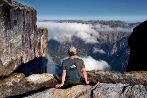 Tourist enjoying spectacular views of fog-shrouded Lysefjord, Lysefjord, Rogaland, Norway