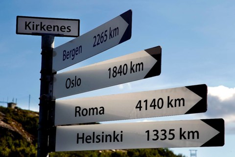Guide in Kirkenes shows distances to various cities under blue skies, Kirkenes, Finnmark, Norway