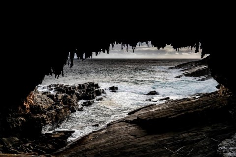View of the ocean and rugged coastline through the dark cave of Admiral's Arch, Kangaroo Island,