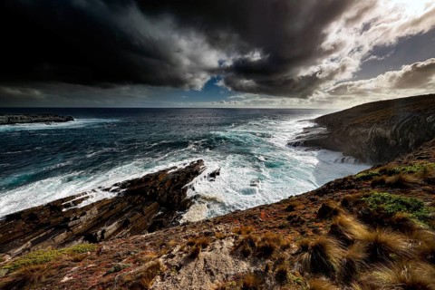 Stormy sea meets impressive coastal cliffs under impending clouds, zero