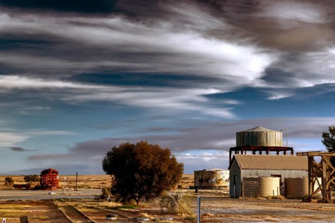 Industrial building with water tower in rural Marree under dramatic sky, Marree, South Australia,
