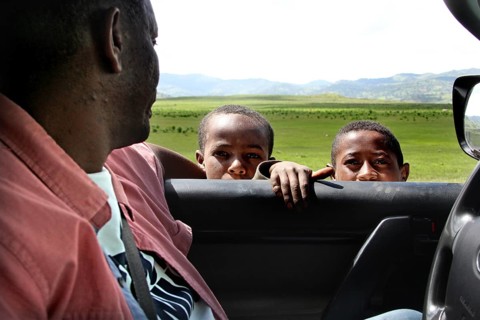 Man in car, two children looking through window in green landscape in the Bale Mountains, Bale