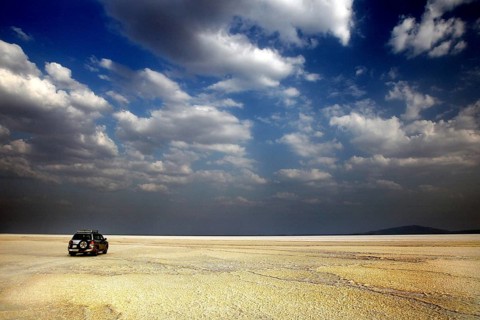 Land cruiser under cloudy sky in wide desert landscape, Dallol, Asale, Ethiopia