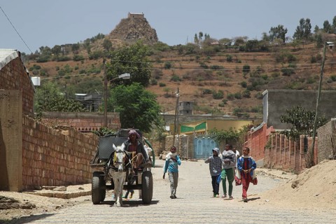 Locals walk down a dusty road surrounded by hills, Axum, Tigray, Ethiopia