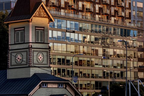 Wooden church in front of a modern glass façade in the Rotermann quarter, reflective architecture