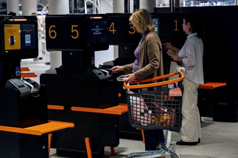 Customers use self-service checkouts with shopping trolleys in the shopping center, Tallinn, South