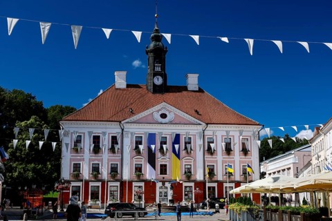 Impressive Tartu City Hall with red roof and flags on lively Town Hall Square, Rathausplatz,