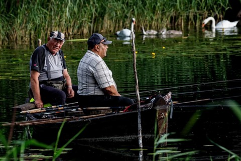 Two anglers sit in a rowboat on Lake Ilgis, surrounded by reeds and nature, Ignalina, Lithuania