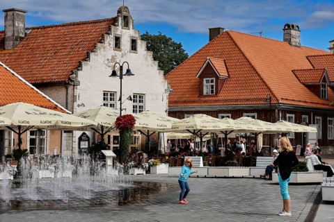 Lively scene in front of the historic Weighouse with people and fountains, Kuressaare, Saaremaa,