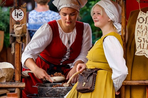 Saleswomen in traditional costumes serve customers at a medieval market, Tallinn, Harju, Estonia