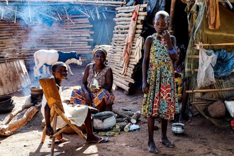 Women and children in the village, a woman preparing a meal surrounded by smoke and traditional