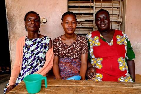 Three woman sitting together at a table smiling and enjoying company, Bouké, region, Côte d'Ivoire