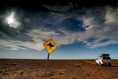 Kangaroo warning sign in an open, cloudy desert landscape near an off-road vehicle, Breakaways,