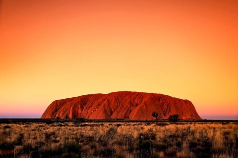 Uluru at sunset in the orange sky of the Australian outback, Uluru, Northern Territory, Australia