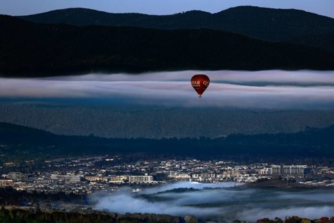 View of Canberra from Mount Ainslie Lookout with a hot air balloon against a mountainous backdrop,