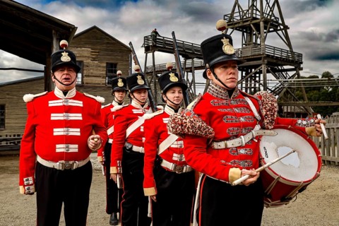 Soldiers wearing historic red uniforms in front of a gold mine in Sovereign Hill, Ballarat,