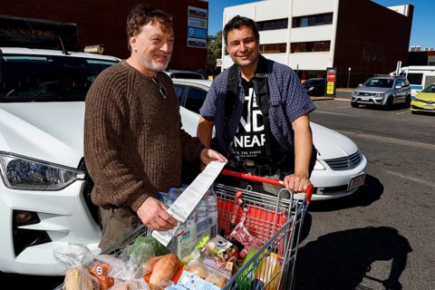 Two men shopping in front of a Coles supermarket in a happy mood, Alice Springs, Northern