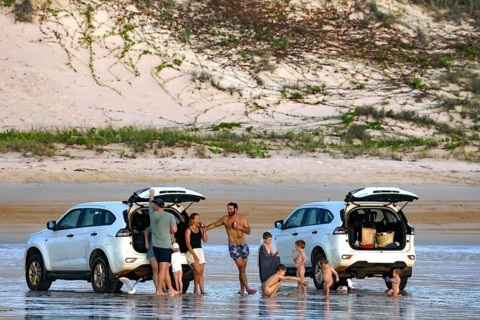 Beach visitors stand next to cars on the sandy beach of Cable Beach, Broome, Broome, Western
