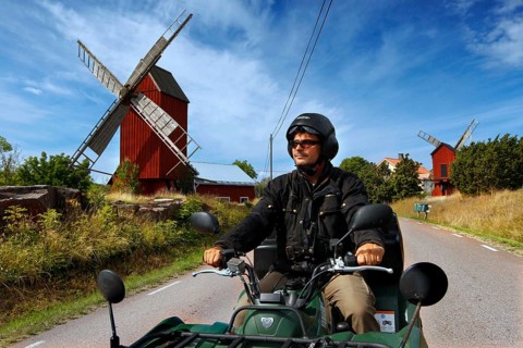 Man riding on ATV along a road with distinctive windmills, Långnäs, Åland, Finland