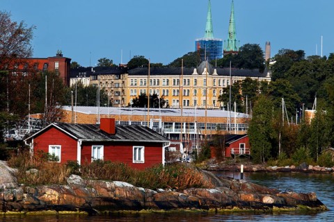 Red wooden house on a Helsinki island surrounded by water and lush greenery, Helsinki, Finland
