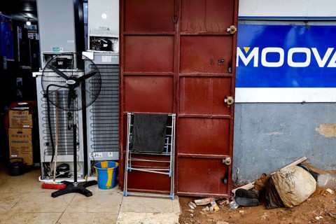 A locked door in an urban environment surrounded by dirt and scattered objects, Bouaké, Côte