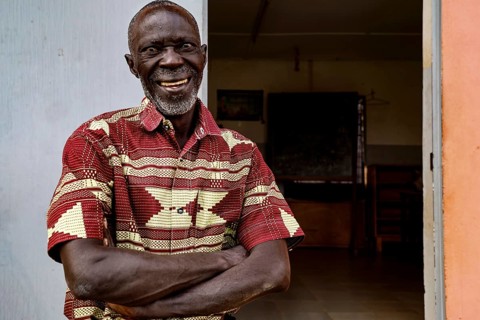 Smiling man in traditional dress standing happily at a door, Bouaké, null, Côte d'Ivoire
