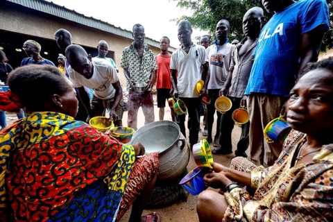 Men standing and sitting serving food at Saint Camille men's psychiatry, Bouaké, Côte d'Ivoire