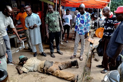 Homeless person receives care on the street, surrounded by helping people, CI Bouaké, Ivory Coast