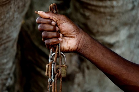 A hand firmly holds a heavy chain as a symbol of suffering, Bouaké, Ivory Coast