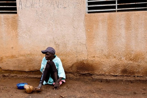 A patient sits alone with a plate against a wall, Bouaké, Nimbo, Côte d'Ivoire