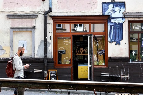 Passerby walks past a cafe in Uzupis, Vilnius, mural in the background, Vilnius, Vilnius County,