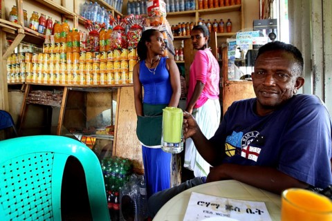 Man enjoying a drink in a cozy juice bar surrounded by laughter, Bahirdar, Ethiopia
