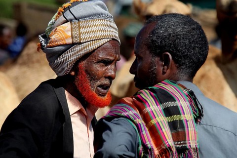 Merchants have a conversation at the colorful camel market in Babile, surrounded by herds of