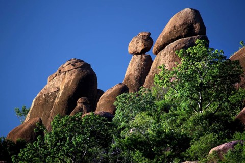 Steeply rising rocks surrounded by lush vegetation under bright blue skies, Babile, Oromia,