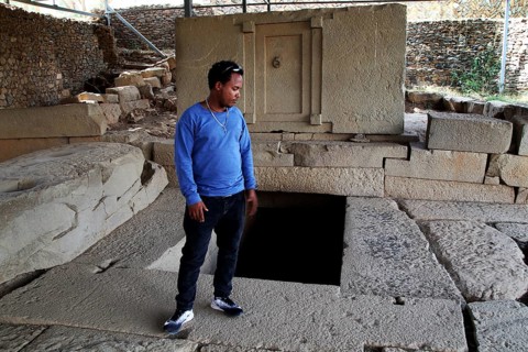 Guide Raphael shows ancient ruins in Axum's Stelenpark, known as Tomb of the False Door, Axum,