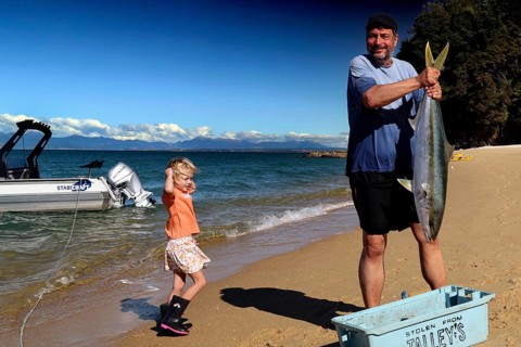 A man keeps a big fish on the beach in Appletree Bay, Abel Tasman National Park, South Island, New