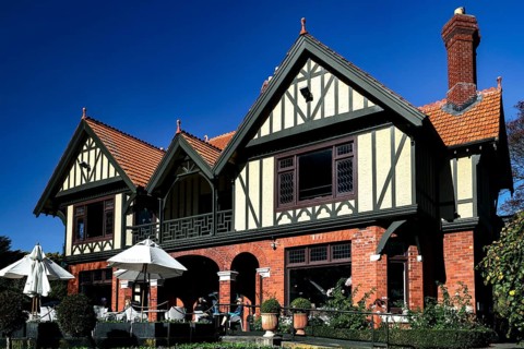 Historic Tudor style building with red bricks under blue sky in Mona Vale, Christchurch, Mona Vale,