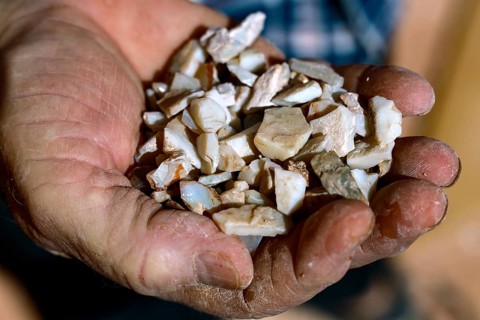 Unprocessed opalns presented in one hand, remnants of opal mining, Coober Pedy, South Australia,