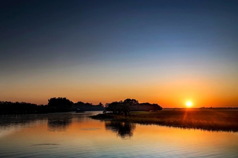 A clear sunrise is reflected in the water in Kakadu National Park, Kakadu National Park, Northern